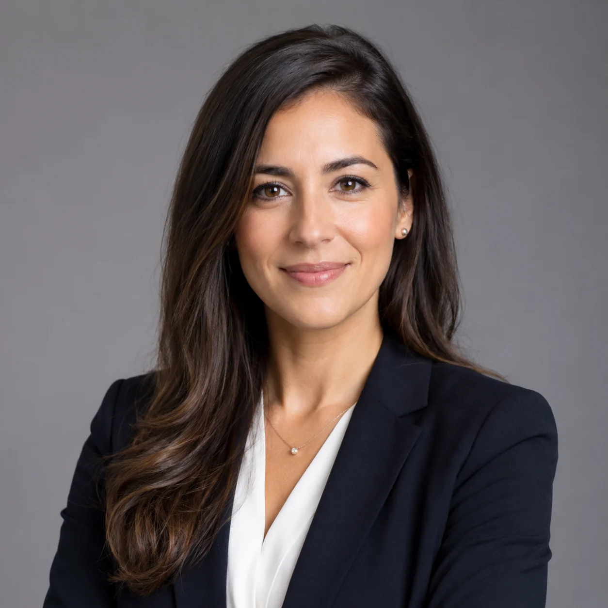 Professional woman in a business-casual LinkedIn headshot with soft daylight and a neutral gray background showing a calm, confident expression